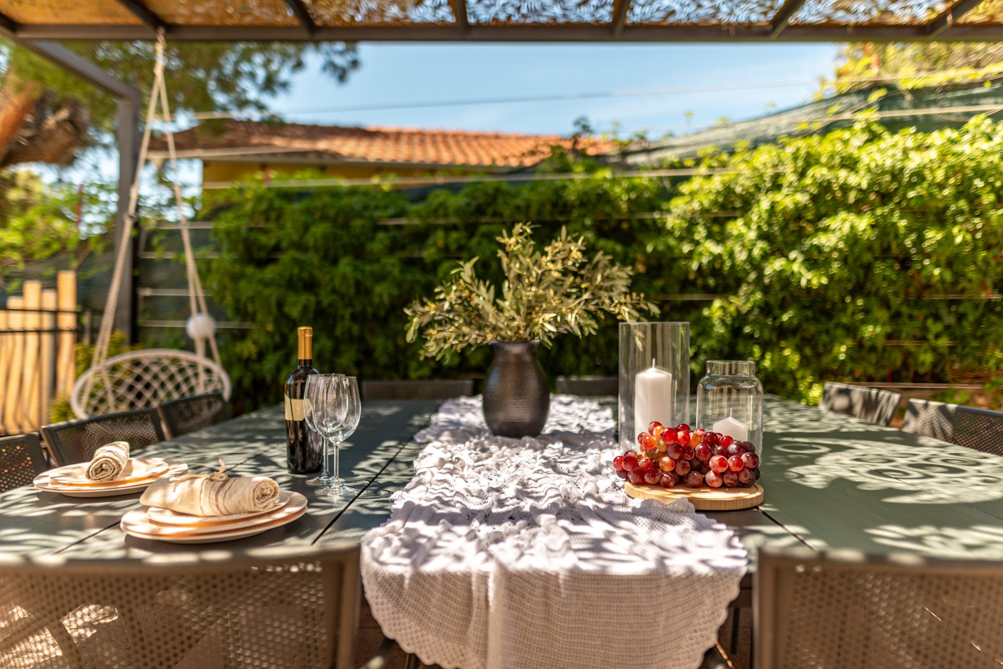 Outdoor dining table set with wine, fruit and candles on the shaded terrace of the villa in Dalmatia